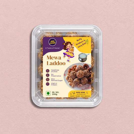 VERU Foods Mewa Laddoo sealed in a transparent PET tray with the Mewa Laddoo label and laddoos visible through the packaging on a soft pink textured background.